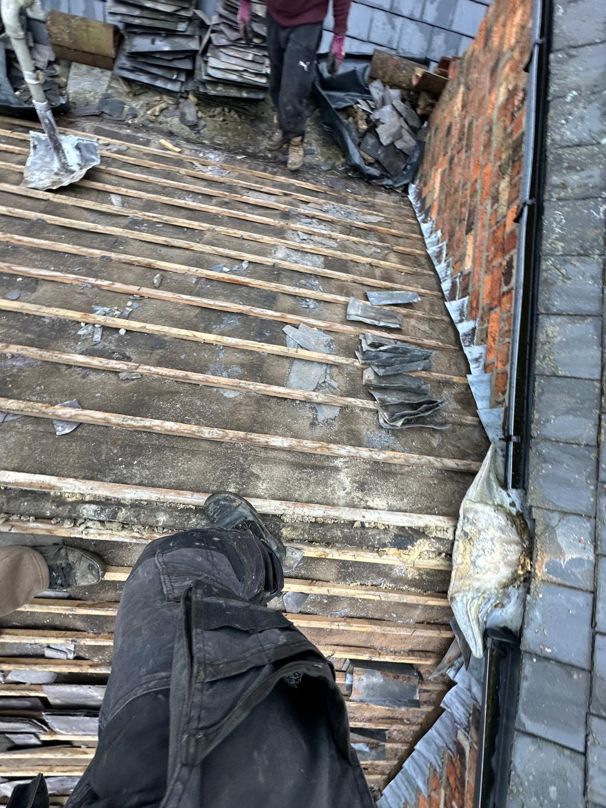Old slates being removed and stacked during a full slate roof strip