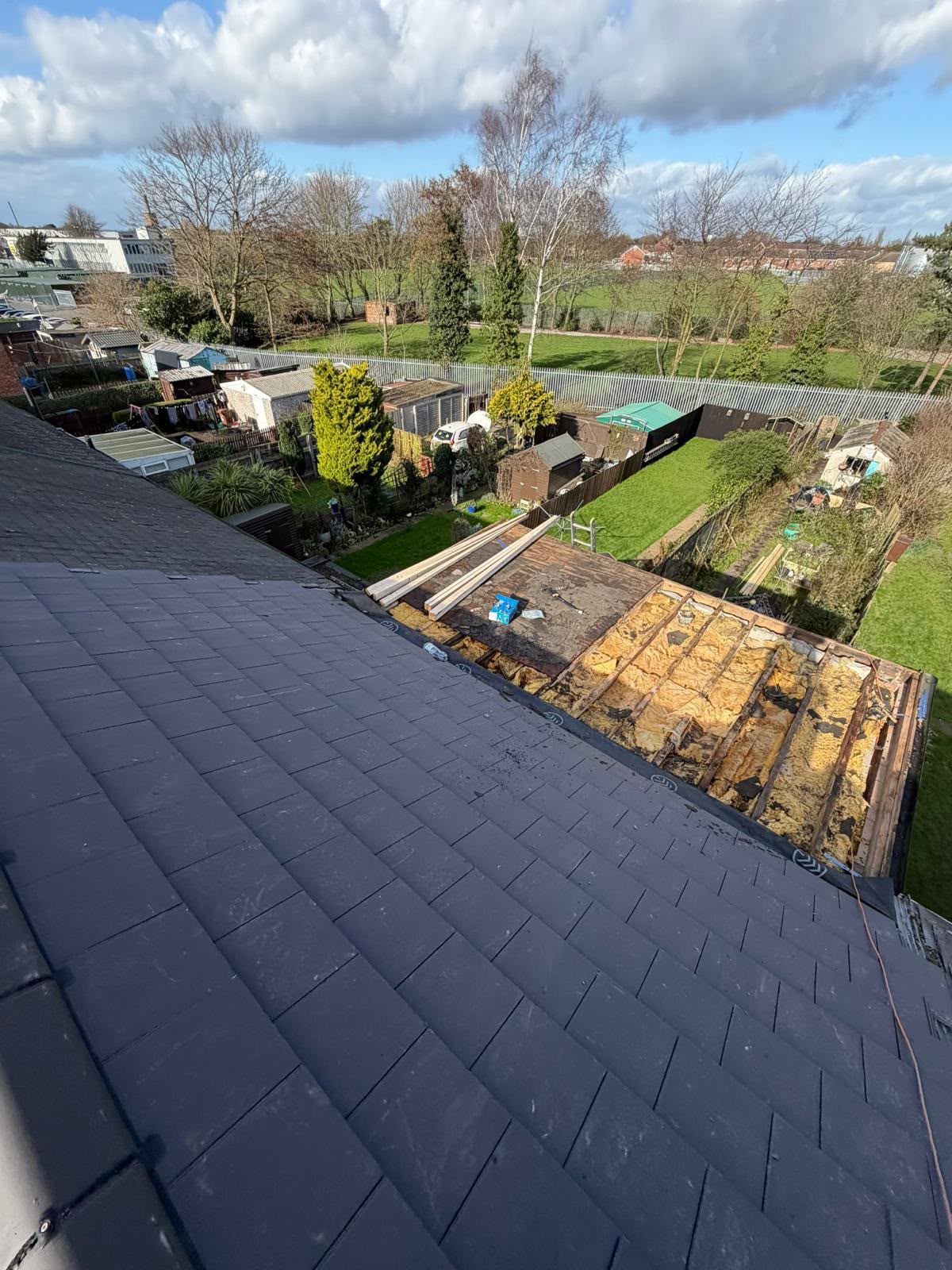 Re-roofing project in progress with old slates being stripped and new tiles going down