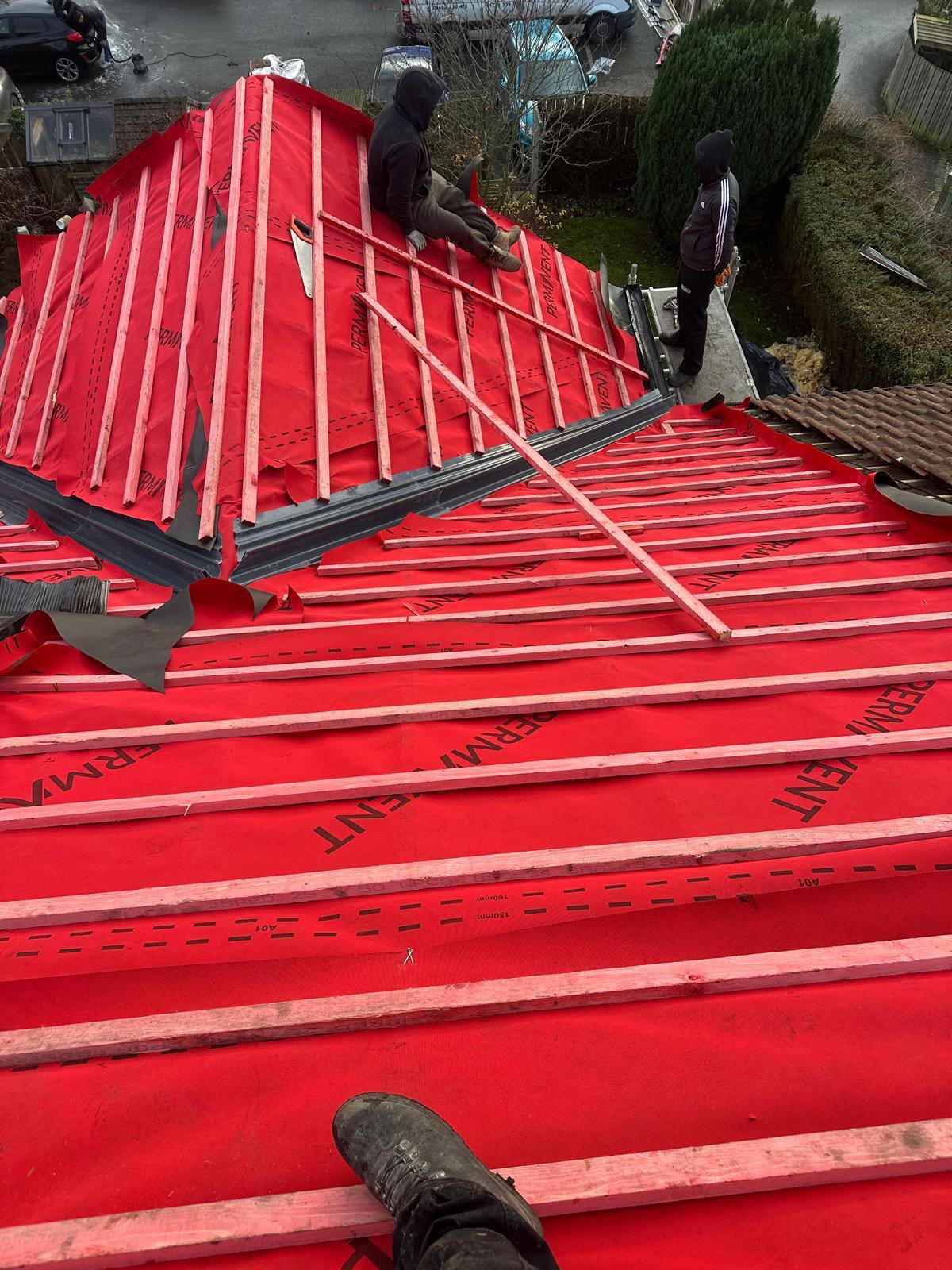 One Stop Roofing team fitting red membrane and battens around a complex roof hip