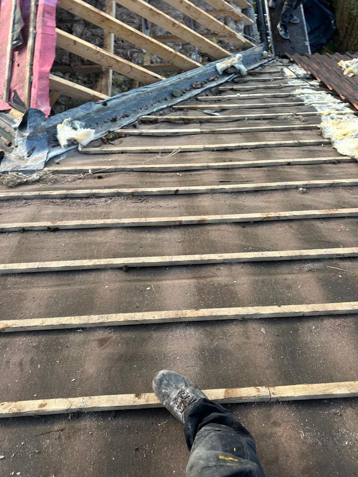 Roof strip exposing old timber laths, insulation and a lead valley before renewal