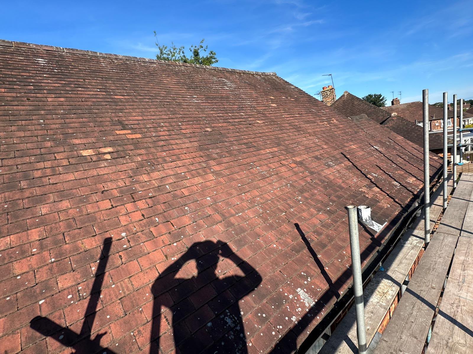 Old red tiled roof heavily weathered with moss growth before a full replacement in Yorkshire