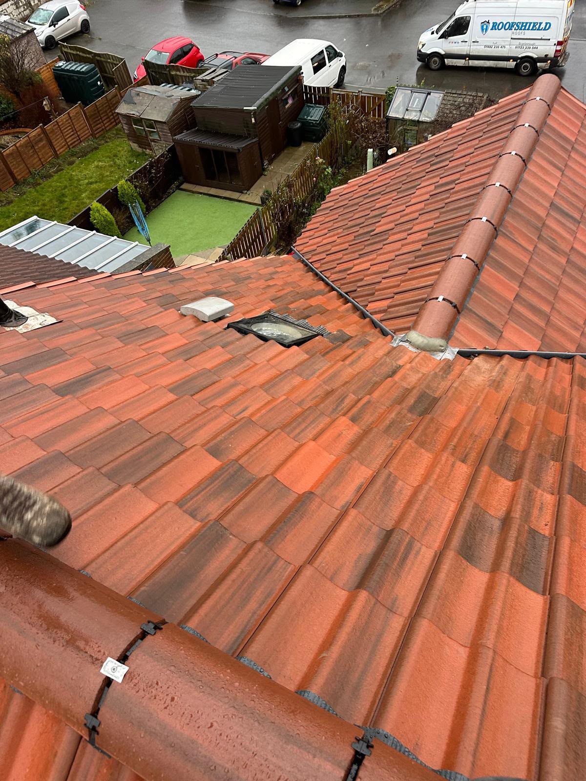 Wide view of a new red tiled roof showing ridge, hip and rooflight detailing
