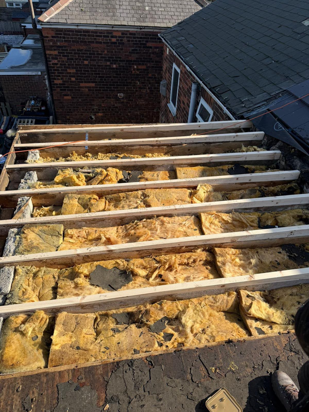 Roof strip exposing timber rafters and loft insulation during a full re-roof