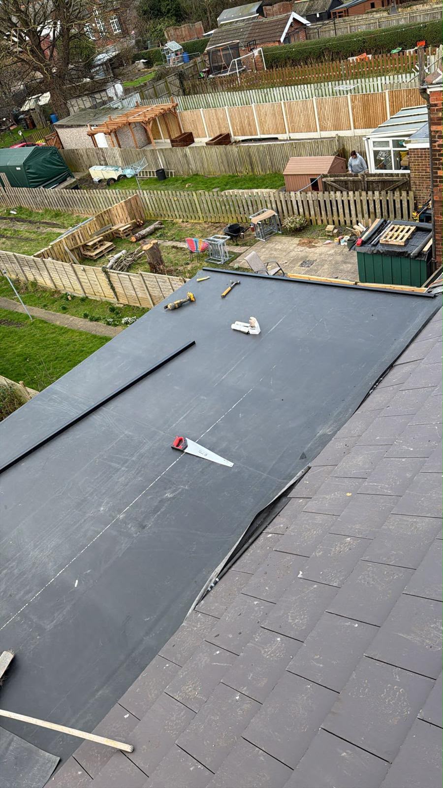 Black EPDM rubber membrane being laid onto a flat roof section by One Stop Roofing